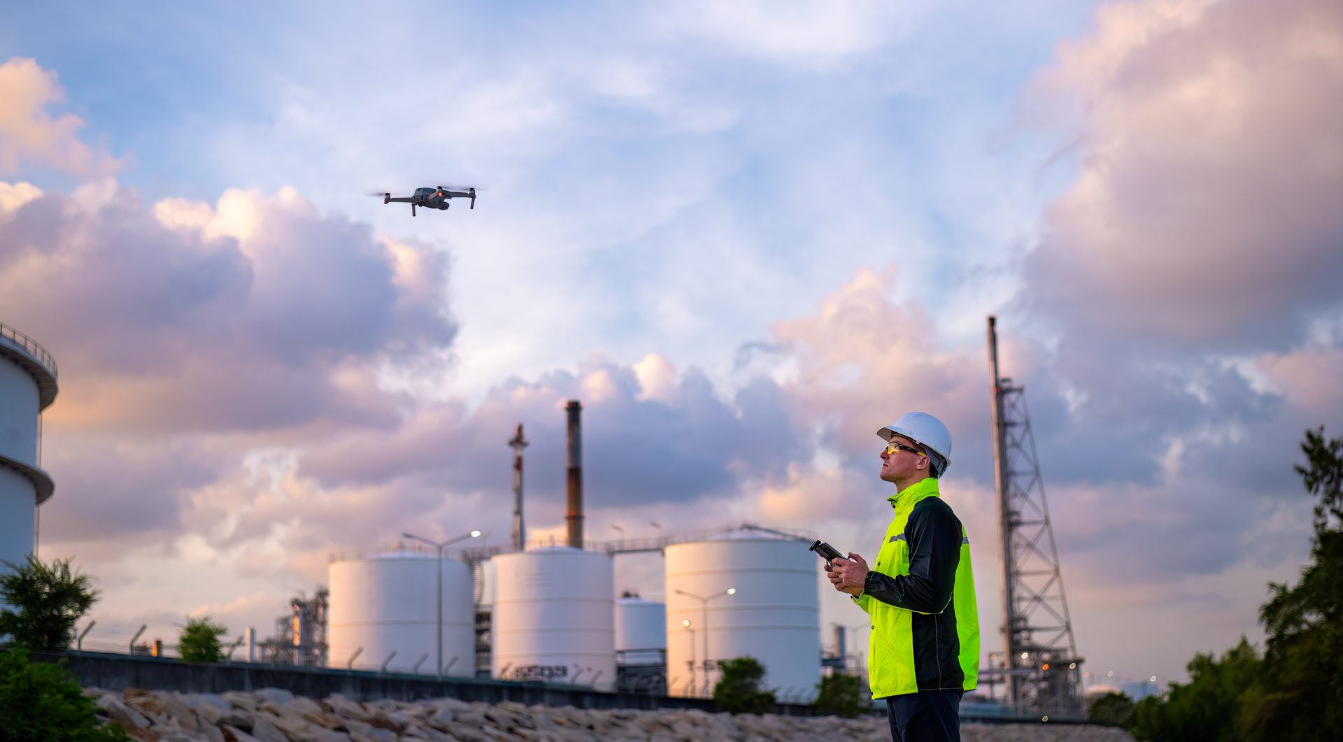 Dron sobrevolando una instalación industrial con un técnico en primer plano